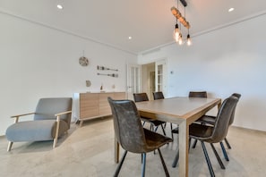 A modern dining area with a wooden table and leather chairs, a white cabinet with decorative items, and a unique light fixture.