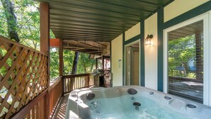 Un jacuzzi bajo un techo con una terraza de madera y vistas a árboles.