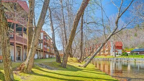 Vista del río con un edificio que tiene balcones y una zona verde.