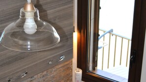 A kitchen with a stainless steel sink, a hanging pendant light, and a window with a view of a balcony. - Balcony Bellavista B - Holiday home by the sea (Cefalù)