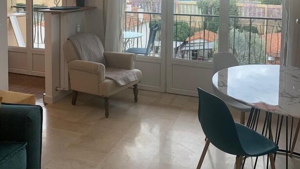 Ein geräumiges Wohnzimmer mit großem Fenster, einem Esstisch und einer Couch.