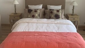 Ein Schlafzimmer mit einem großen Bett, zwei Nachttischen mit Lampen, einer gewobenen Deckenleuchte und einer schlichten Wand.