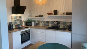 Eine moderne Küche mit weißen Schränken, einem Einbauofen, einer Mikrowelle, einem Spülbecken und einer Pendelleuchte.