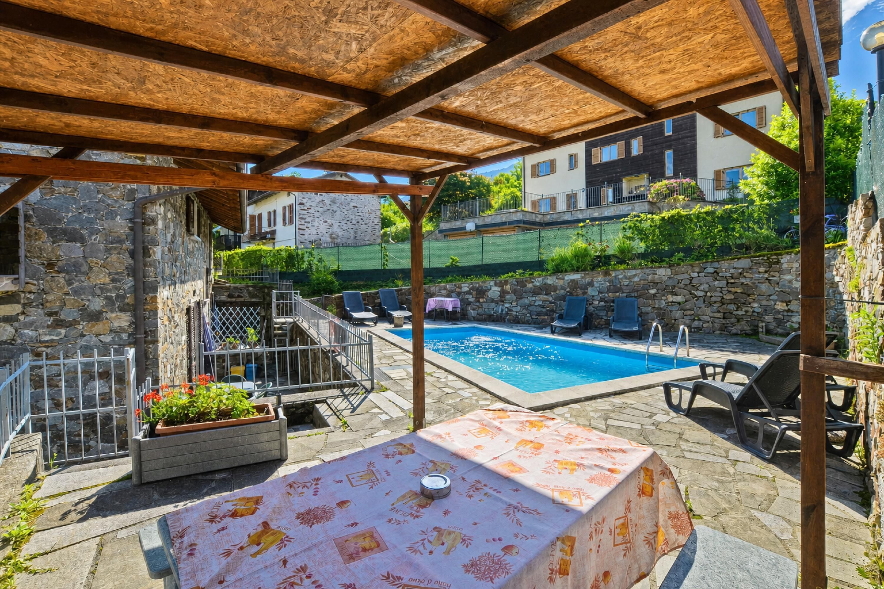 A covered outdoor area with a pool, stone walls, and lounge chairs.