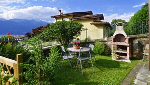 A patio with a table and chairs, a stone oven, and a view of mountains.