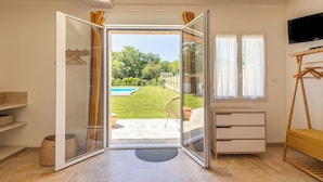 A room with a sliding glass door leading to a backyard with a pool and greenery.