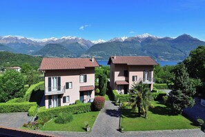 A residential area with two houses, a paved driveway, and a mountain backdrop.