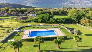 Una piscina circondata da un prato curato, con vista sulle montagne e su un lago sullo sfondo.