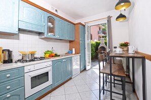 A kitchen with blue cabinets, a stove, and a dining area with a table and chairs.