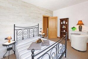 A bedroom with a bed, bedside tables, a wardrobe, a desk, a chair, and a lamp.