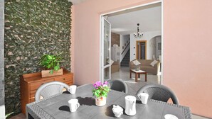 Un coin repas avec une table dressée pour quatre personnes, un buffet en bois et une plante en pot.