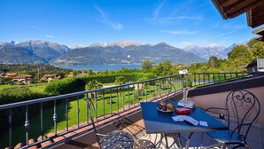 Un balcon avec une table, des chaises et une vue sur les montagnes et un lac.