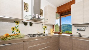 A modern kitchen with a gas stove, stainless steel appliances, and a window with a mountain view. - Casa Virginia, Mandello del Lario, Italy (Mandello del Lario)