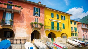 A canal with boats docked, colorful buildings with balconies, and arches. - Casa Virginia, Mandello del Lario, Italy (Mandello del Lario)