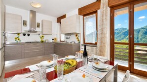 A modern kitchen with a dining area, large windows, and a view of mountains. - Casa Virginia, Mandello del Lario, Italy (Mandello del Lario)