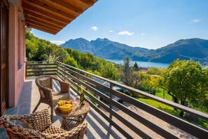 A balcony with wicker furniture, a bottle, and fruit. - Casa Virginia, Mandello del Lario, Italy (Mandello del Lario)