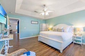 Quarto com cama, ventilador de teto, mesa de cabeceira e um biombô decorativo.