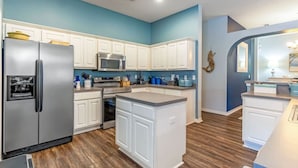 Una cocina moderna con armarios blancos, electrodomésticos de acero inoxidable y una pared de acento azul.