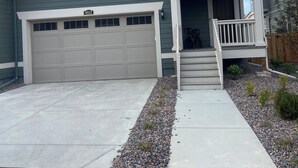 A two-story house with a garage, a front porch, and a small garden area. - Beautiful 2022 Constructed Patio Home. Sleeps up to 6 people. 10mins DIA Airport (Commerce City)
