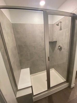 A glass-enclosed shower with a white base and grey tiles. - Beautiful 2022 Constructed Patio Home. Sleeps up to 6 people. 10mins DIA Airport (Commerce City)