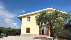 A two-story house with a yellow facade, a wooden door, and a small window. - House of Olives (Lazise)