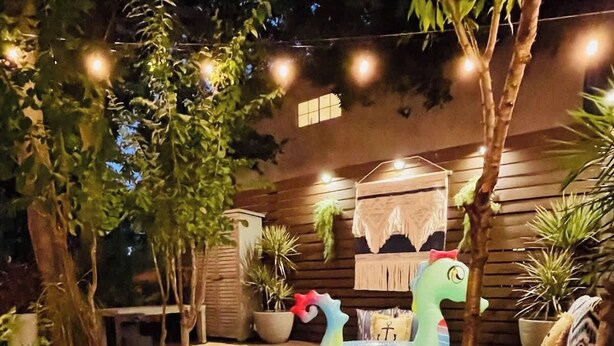 A hot tub with a wooden deck, surrounded by potted plants and a small waterfall feature. - 5BR/CedarPark/Soothing Sauna/HotTub/Peloton (Cedar Park)