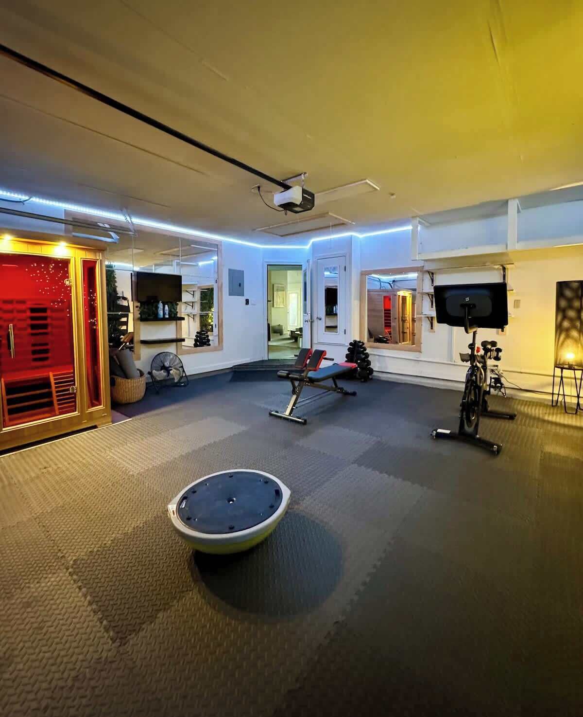 Une salle de sport équipée de matériel d’exercice, d’un projecteur et d’un téléviseur.