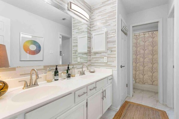 A modern bathroom with a double sink, a large mirror, and a door leading to a shower area. - 5BR CedarPark Soothing Hot Tub (Cedar Park)