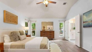 A spacious bedroom with a large bed, a ceiling fan, a dresser, and a view through an open door. - 5BR/CedarPark/Soothing Sauna/HotTub/Peloton (Cedar Park)