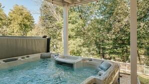 Een hottubgedeelte met een pergola erboven, omringd door bomen.