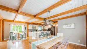 A spacious dining area with a wooden table and chairs, a kitchen in the background, and a 'STAY' sign on the wall. - Beautiful and Private 6000 sqft waterfront home with private dock and hot tub! (Mineral)