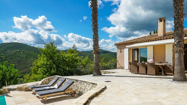 A pool area with lounge chairs and a stone patio.