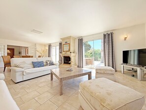 A spacious living room with a fireplace, a television, and a balcony with a view.