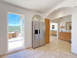 A spacious kitchen with a large refrigerator, wooden cabinets, and a view to an outdoor patio.