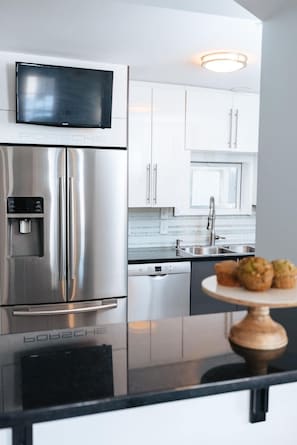 Une cuisine moderne dotée d’appareils électroménagers en acier inoxydable, de meubles blancs et d’un lave-vaisselle Bosch.