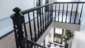 A staircase with black balusters, carpeted steps, and a checkered floor.