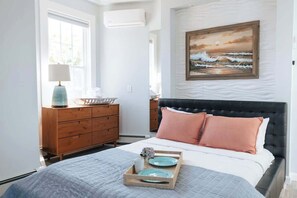 Une chambre à coucher avec un lit, une commode et des œuvres d’art accrochées au mur.