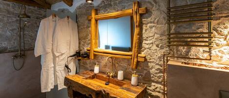 A rustic bathroom with a wooden vanity, a mirror, and a towel rack.
