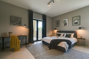 A modern bedroom with a large bed, bedside tables, a desk, and a view through a glass door. - Villa Charm with Pool (Nova Vas)