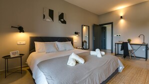 Et moderne hotelværelse med en stor seng, sengeborde, et skrivebord og et spejl.