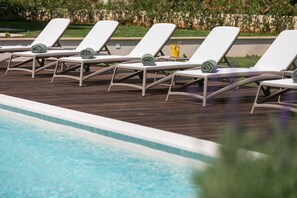 A row of white sun loungers with green towels, a poolside setting, and a glass of orange juice. - Villa Charm with Pool (Nova Vas)
