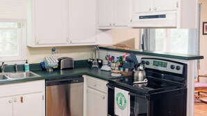 A compact kitchen with white cabinets, a stainless steel dishwasher, a black stove, and a green countertop. - Newly renovated, comfy & artsy! 1mi to Square, 2mi to Campus in old Oxford (Oxford)