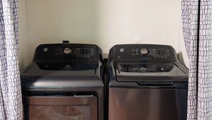 Two stacked washers in a laundry room with a plain wall and patterned curtains. - Newly renovated, comfy & artsy! 1mi to Square, 2mi to Campus in old Oxford (Oxford)