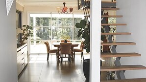 A modern interior with a staircase, a dining area with a table and chairs, and a view through large windows. - Villa (ST NAZAIRE)