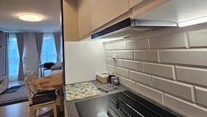 Eine moderne Küche mit einem schwarzen Herd, einer weißen Fliesenwand und einem Essbereich mit Tisch und Stühlen.