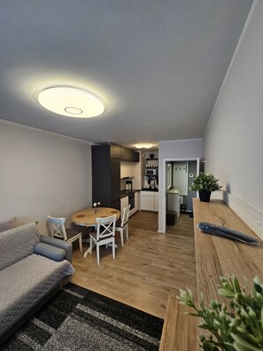 A compact living space with a dining area, kitchenette, and a sofa.