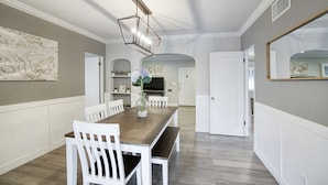 A dining area with a wooden table, white chairs, and a modern chandelier. - ❤️of PHX in Historic Willo • Heated Pool • Chef's Kitchen • Fast WiFi (Phoenix)