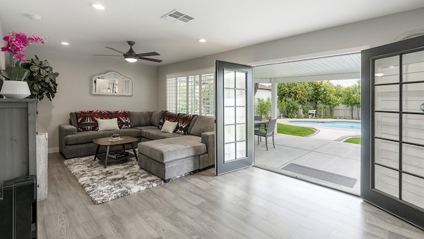 A modern living room with a sectional sofa, a coffee table, and a large sliding glass door leading to an outdoor patio. - ❤️of PHX in Historic Willo • Heated Pool • Chef's Kitchen • Fast WiFi (Phoenix)