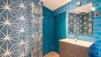 Une salle de bain avec un carrelage aux motifs géométriques, un miroir et un lavabo.