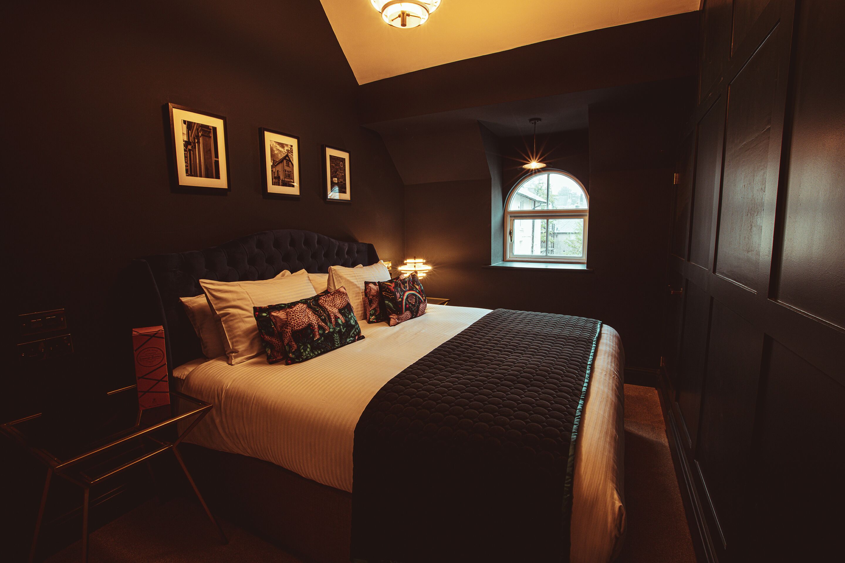 A bedroom with a large bed, a desk, and a window with a view.